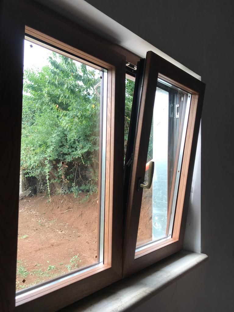 Una finestra con telaio di legno è aperta e si affaccia su un giardino.