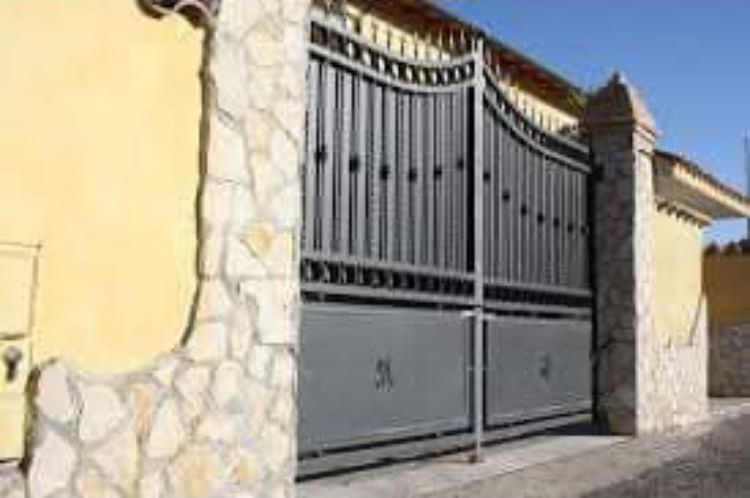 Un grande cancello di metallo è posto di fronte a un muro di pietra.