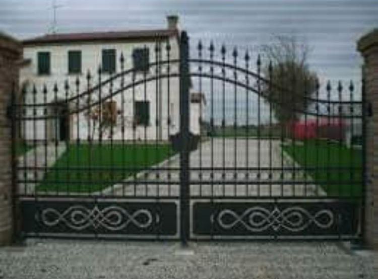 Un cancello in ferro battuto è aperto davanti a una casa.