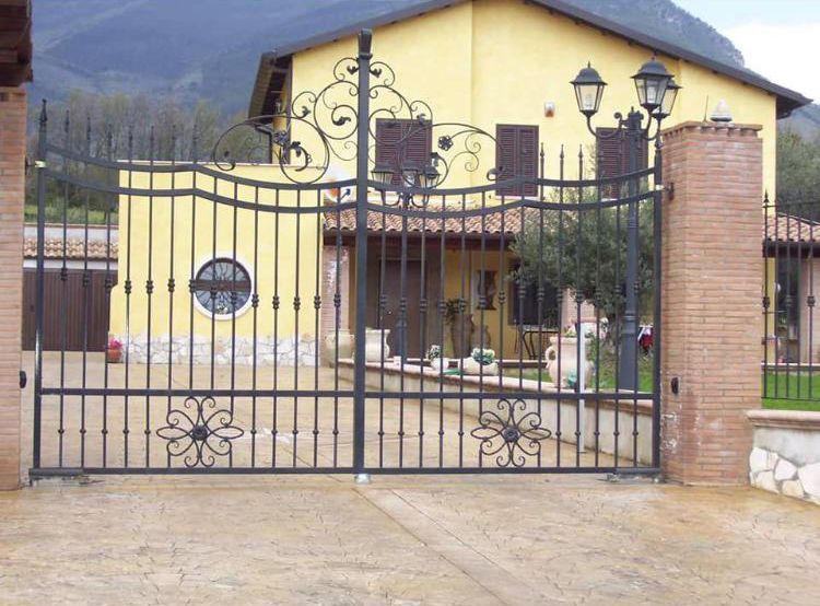 Una casa gialla con un cancello in ferro battuto davanti