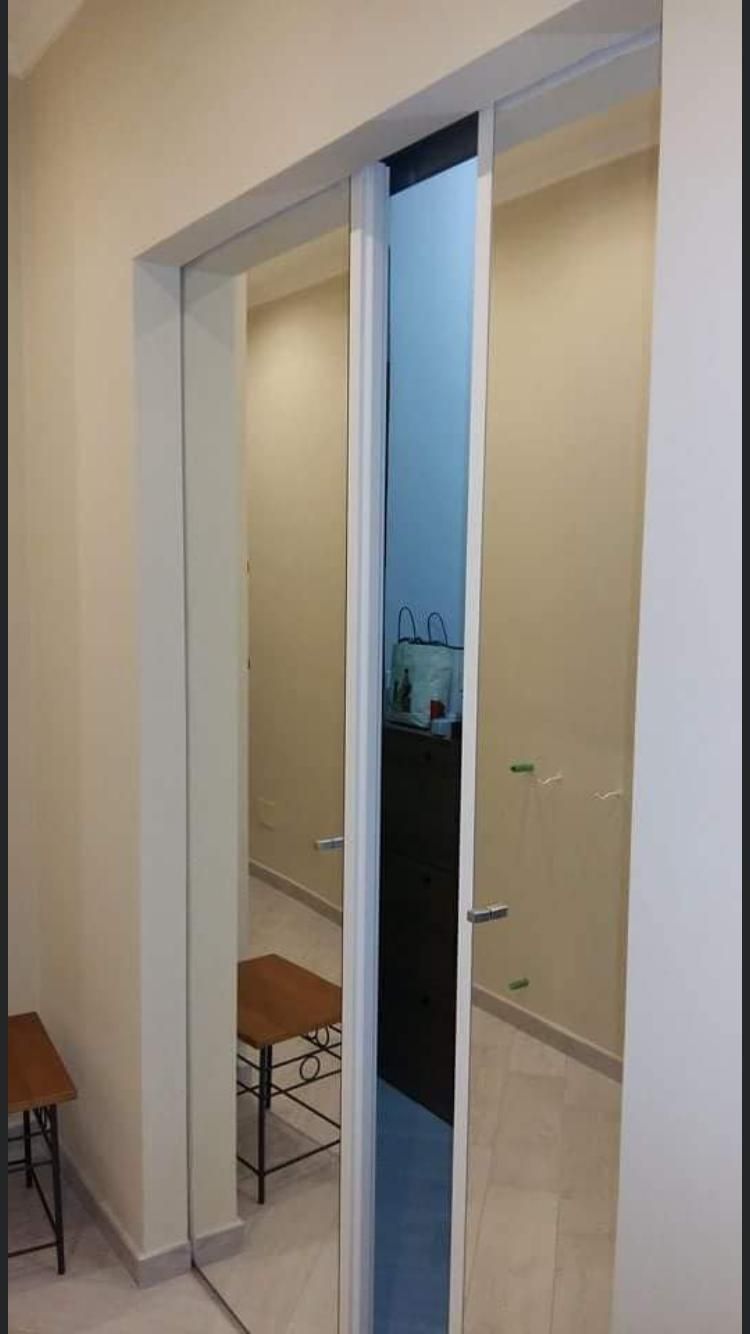 Un corridoio con una porta scorrevole in vetro e uno specchio