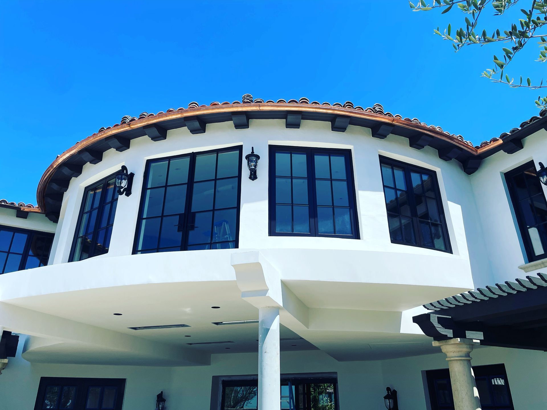 White building with black-framed windows, beneath a blue sky. Copper-colored trim.