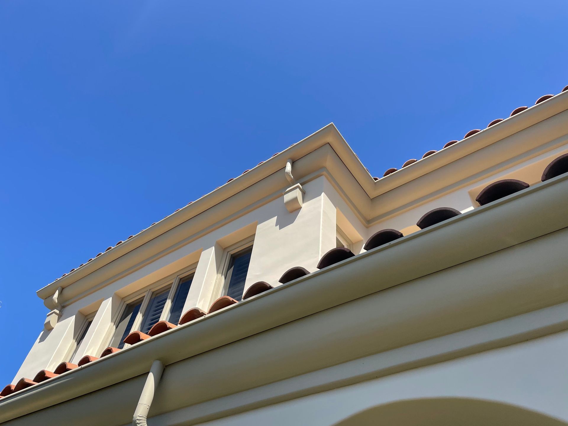 Beige building with red tile roof against a bright blue sky.