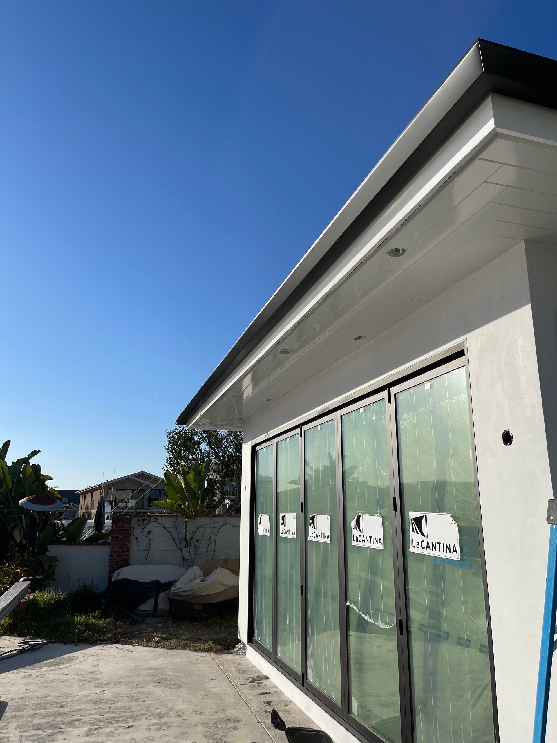 Modern building with glass doors and dark trim against a blue sky.