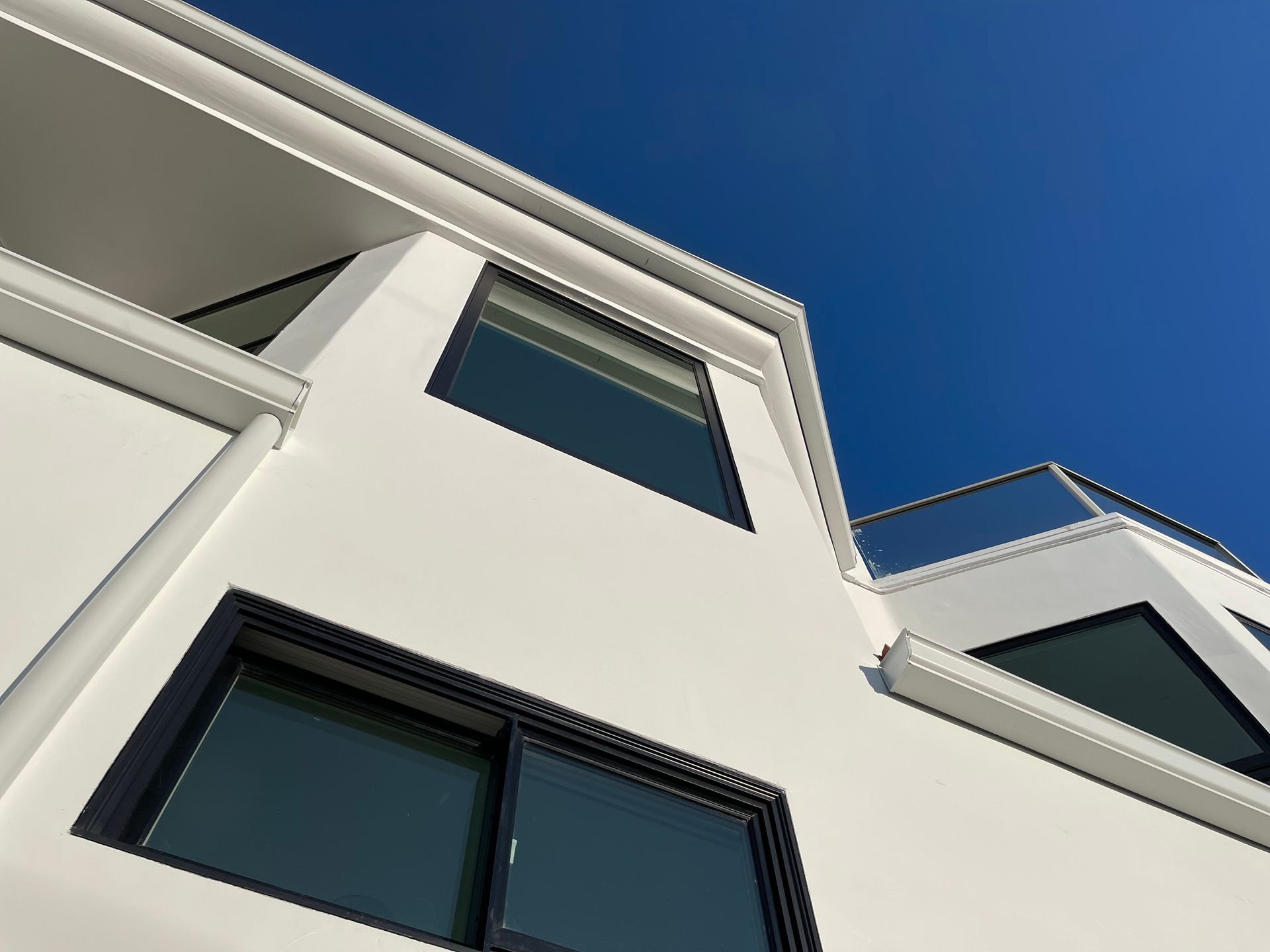 White modern building with black-framed windows against a bright blue sky.