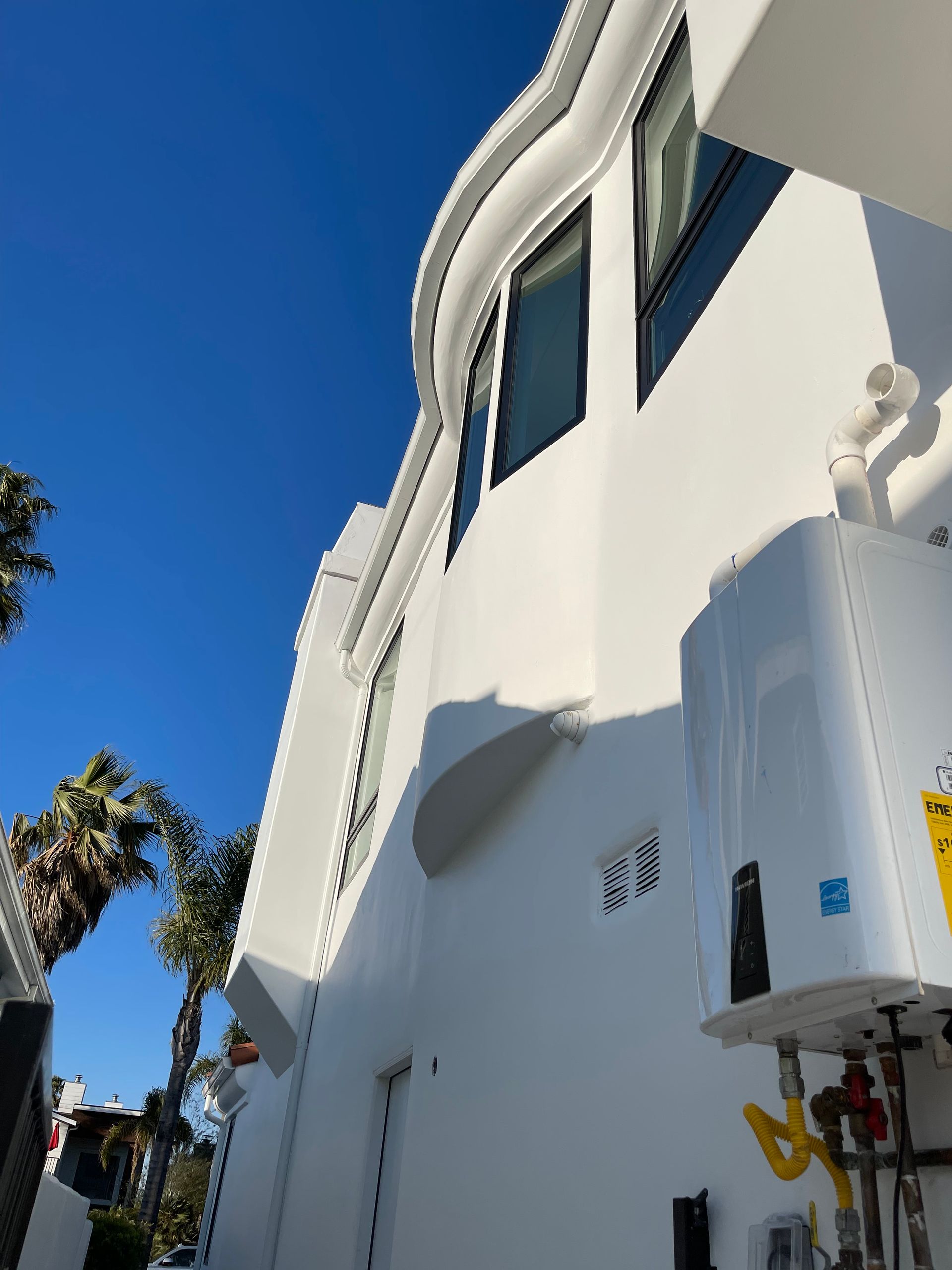 White building with decorative trim, windows, water heater, blue sky.
