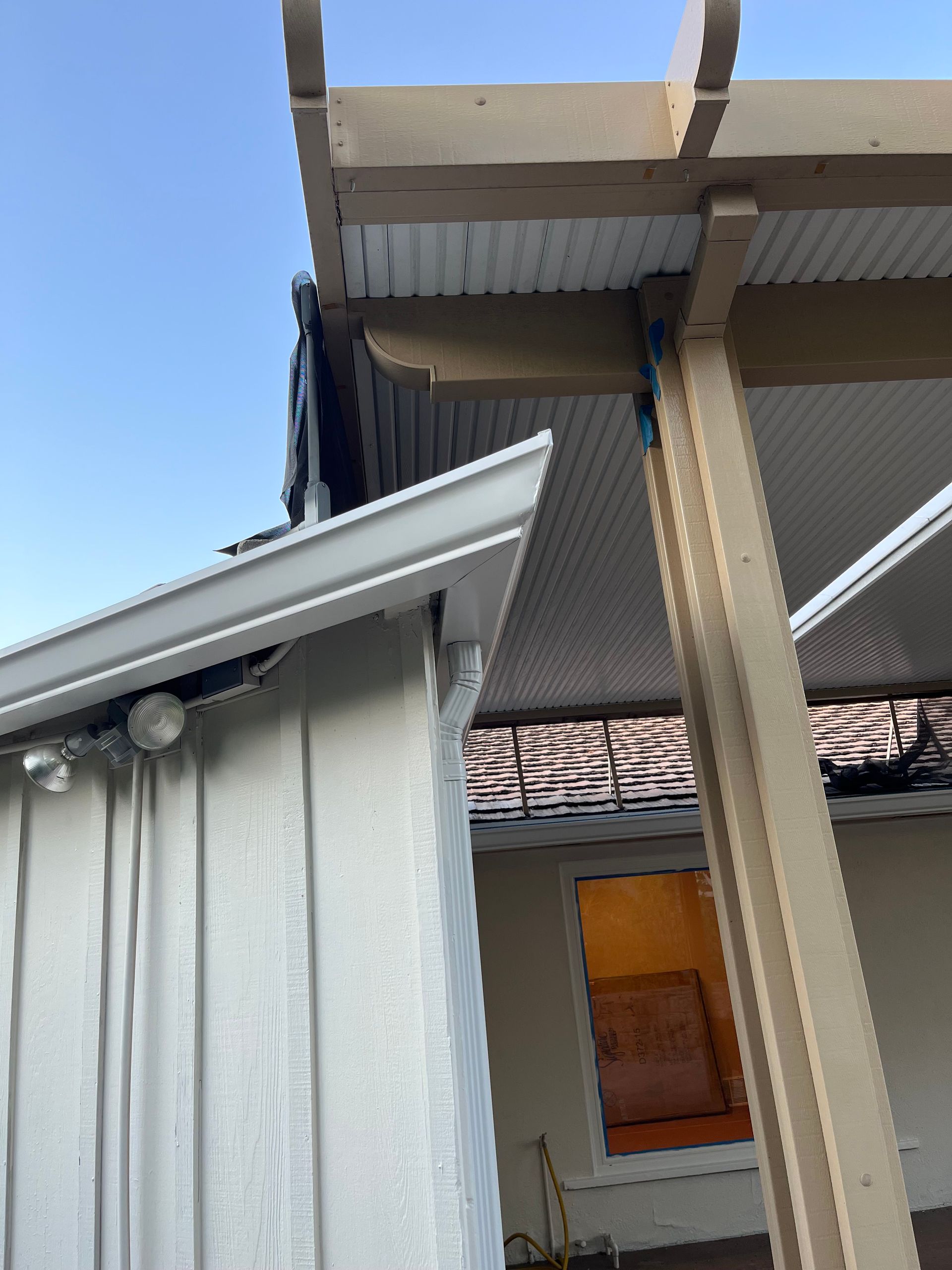 Exterior view of a white house with a pergola and a glimpse of the sky.