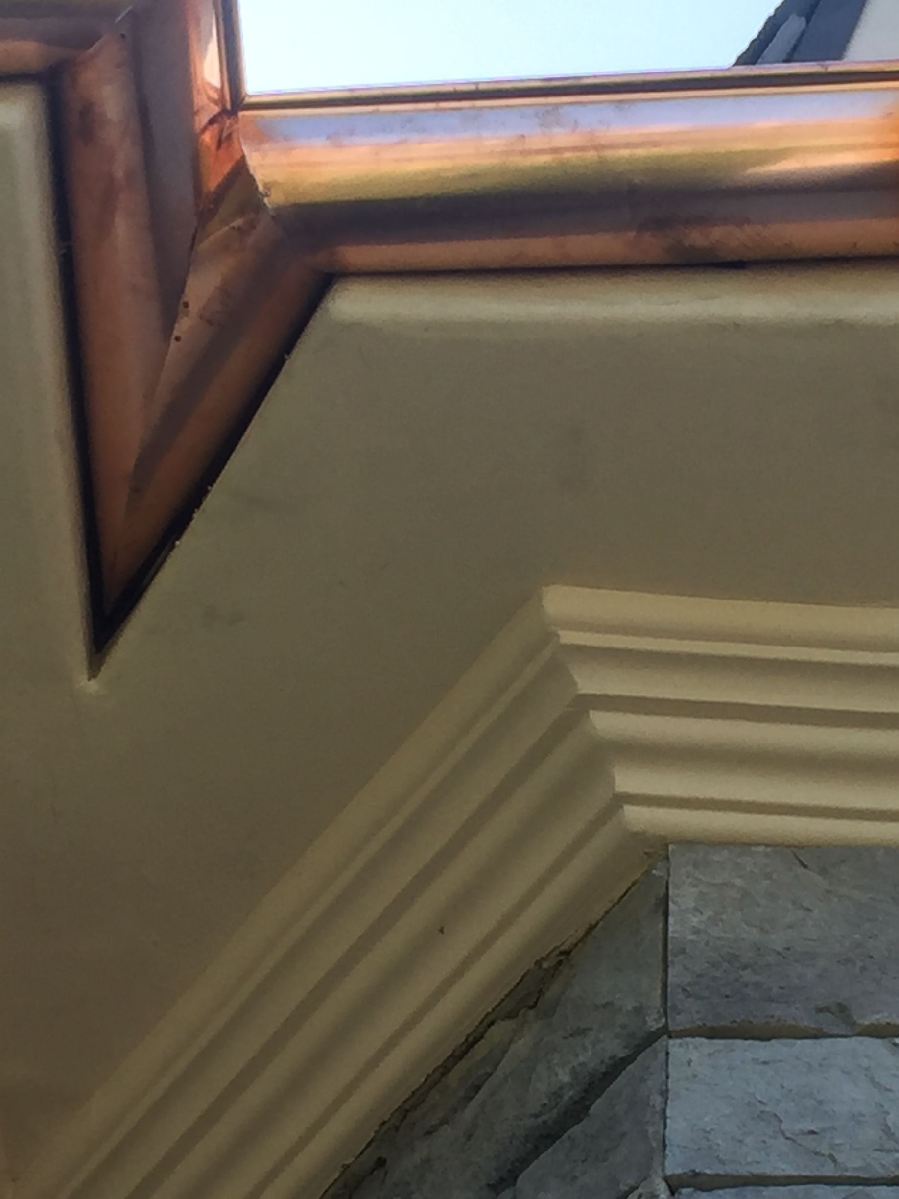 Copper guttering on a beige building exterior with decorative trim.