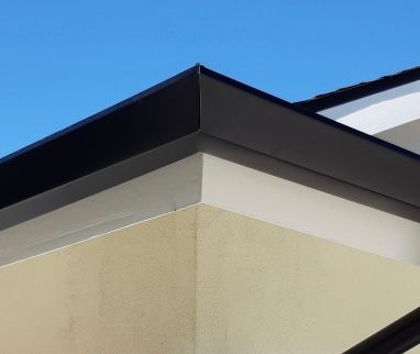 Dark-colored eaves on a cream-colored building corner, against a clear blue sky.