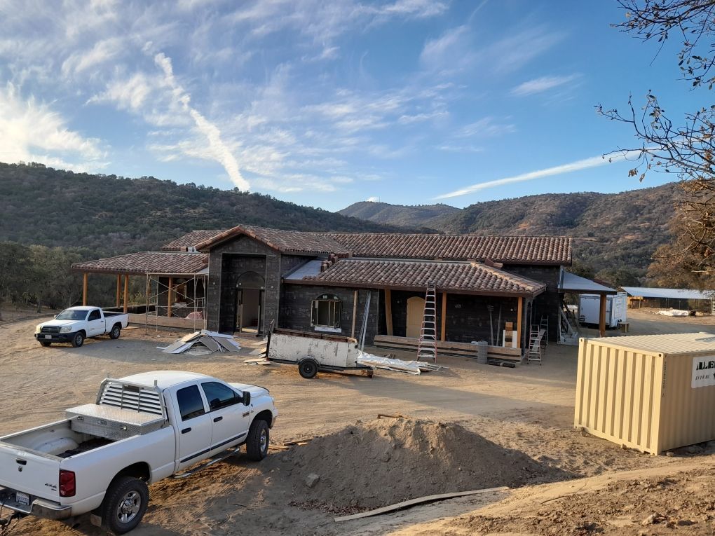 Construction site of a house with trucks. Mountains in the background on a sunny day.