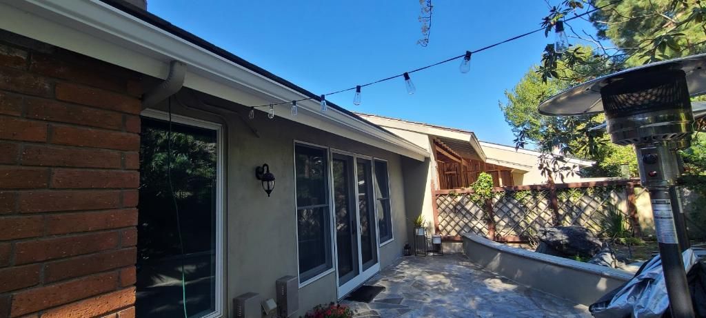 Backyard patio with sliding doors, brick wall, and blue sky.