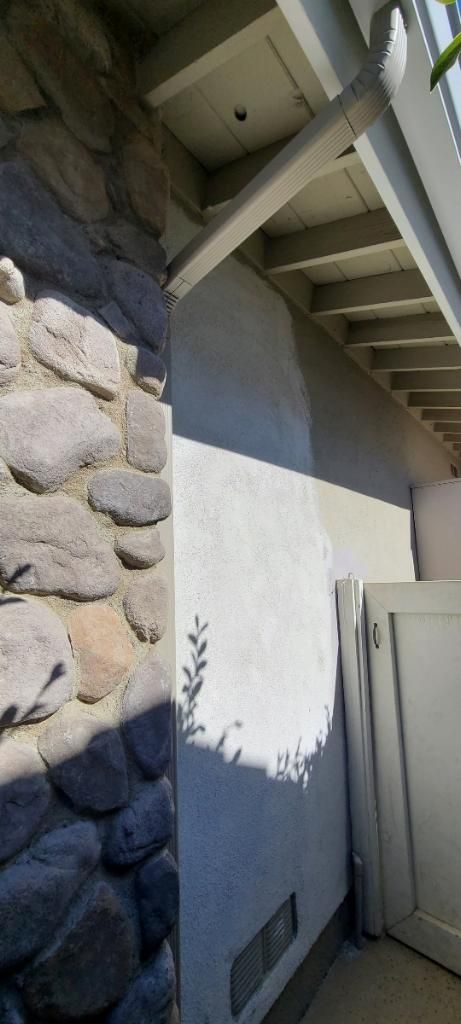 Stone wall and stucco building exterior with wooden support beams.