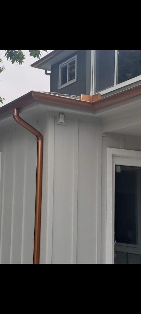 Copper gutters on a white house with dark grey upper level, a close-up view.