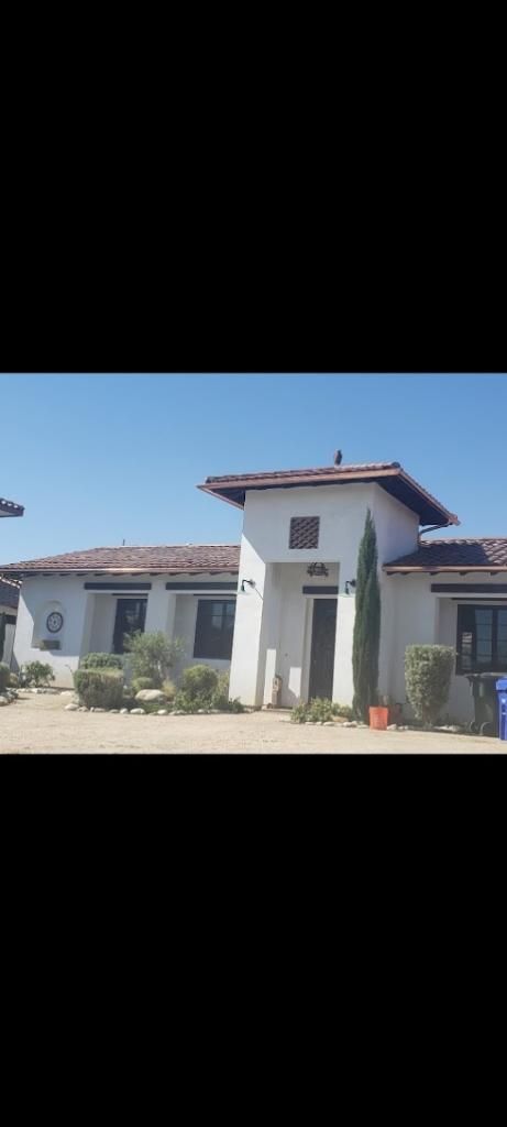 White stucco building with tile roof, tall tower, and blue sky.