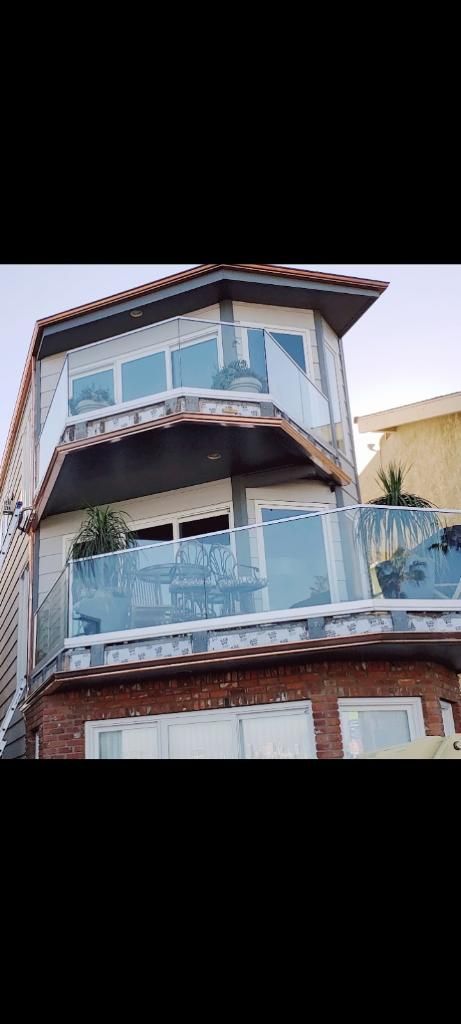 Three-story house with glass balconies and a brick facade.