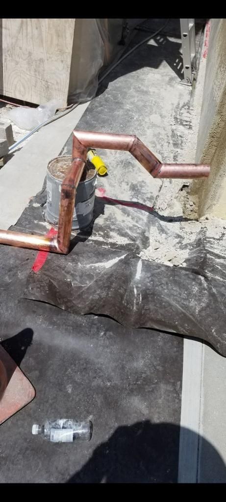 Copper pipes bent in an angular pattern, on a construction site.