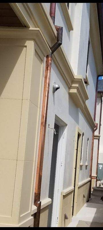 Copper gutters on a building with tan and white walls.