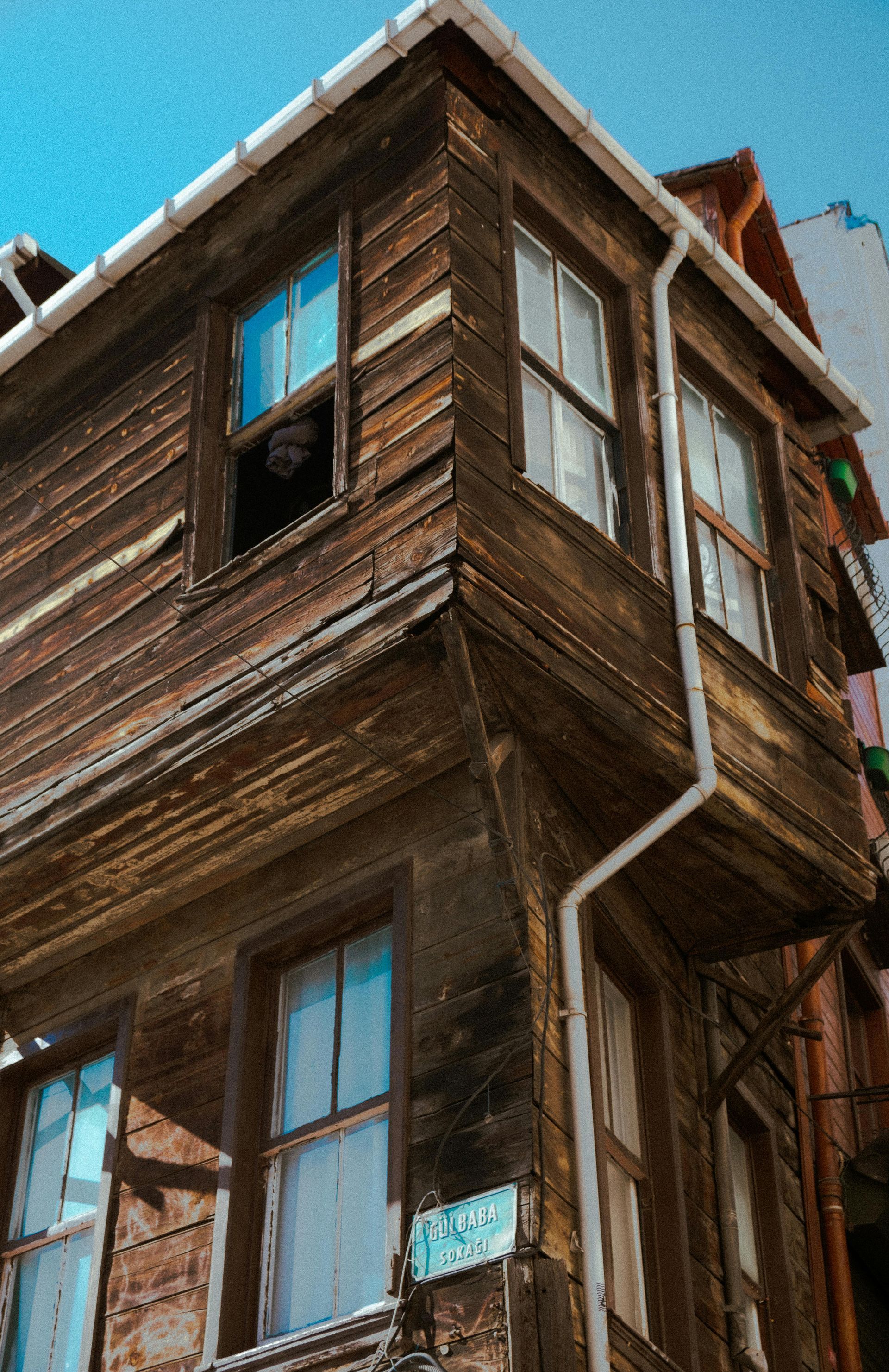 Weathered wooden corner building with multiple windows; blue sky.