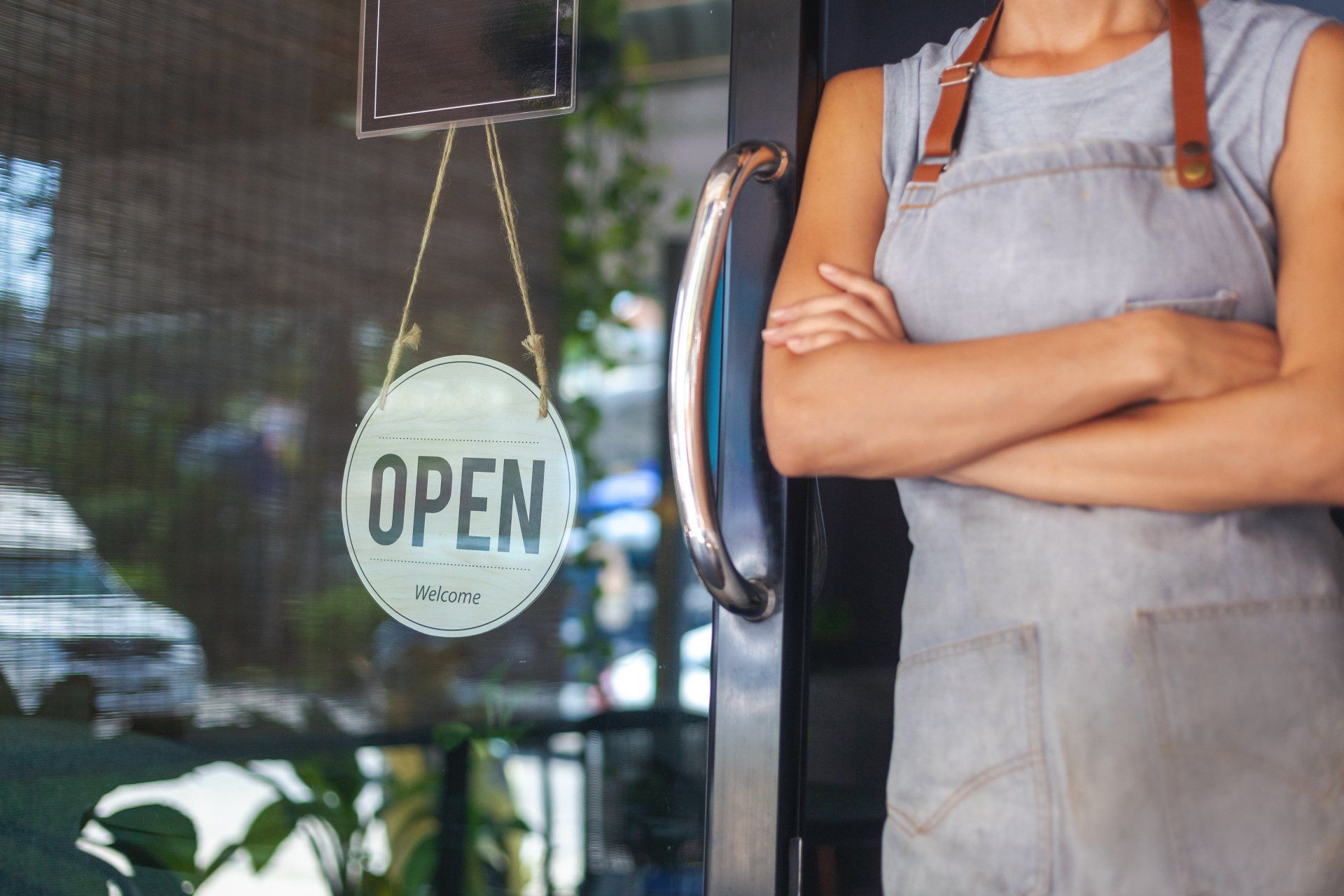 A woman is standing in front of an open sign on a glass door.