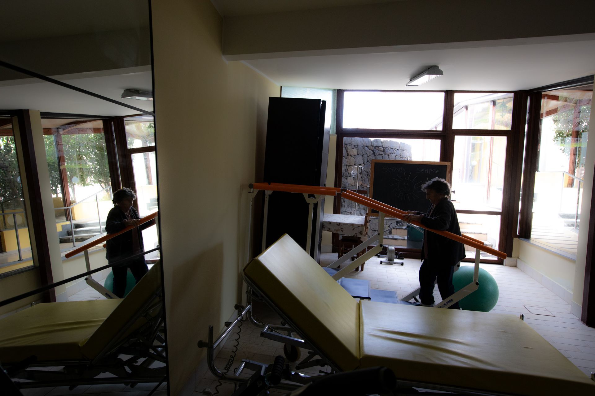 Persona che utilizza una trave di equilibrio in una sala per terapie con specchi e attrezzi ginnici.