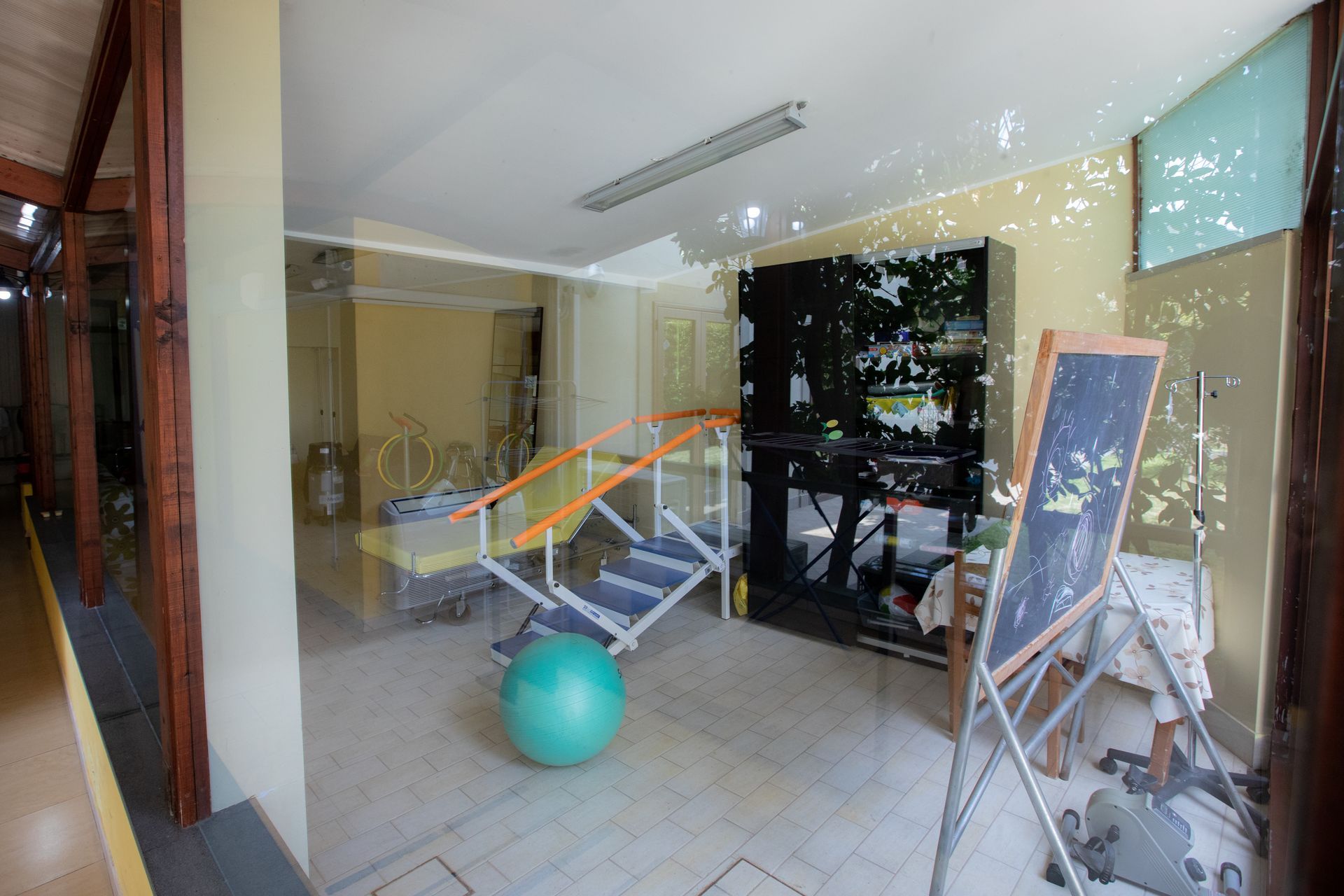 Interno di una sala di fisioterapia con scale, palla da ginnastica e attrezzatura.