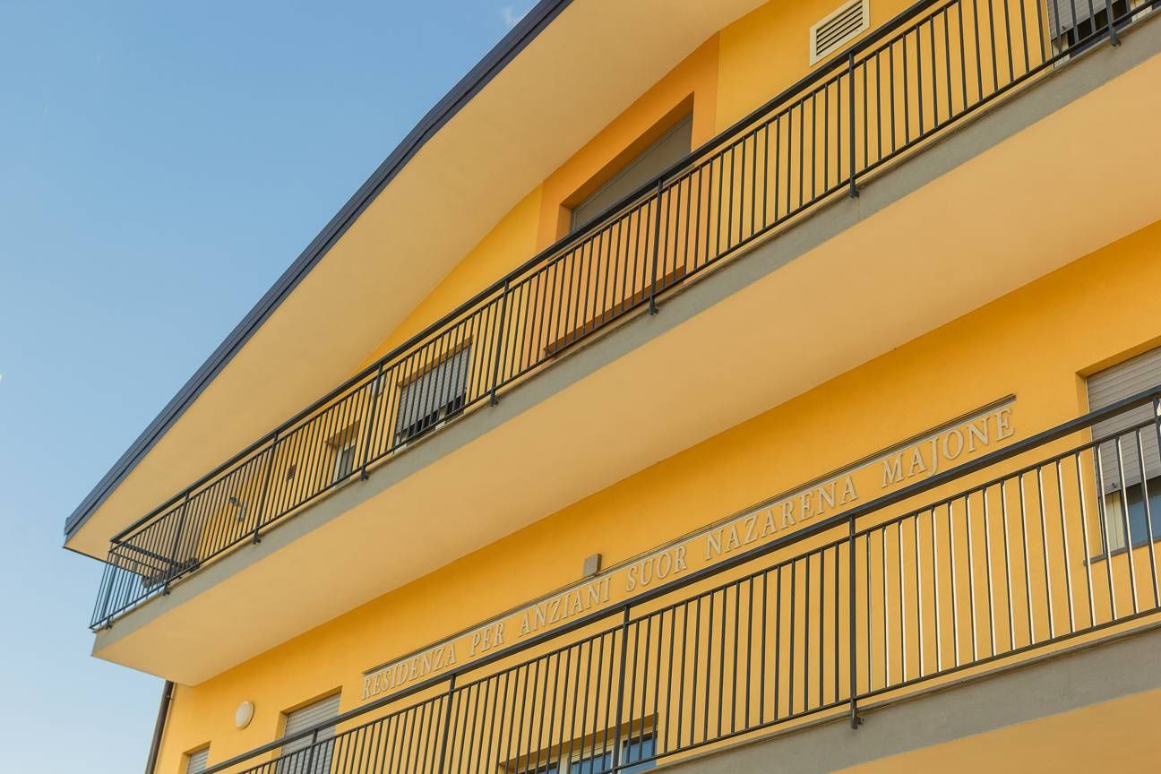 Edificio giallo con balconi in metallo nero contro un cielo blu.
