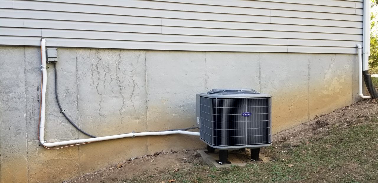 An air conditioner is attached to the side of a house