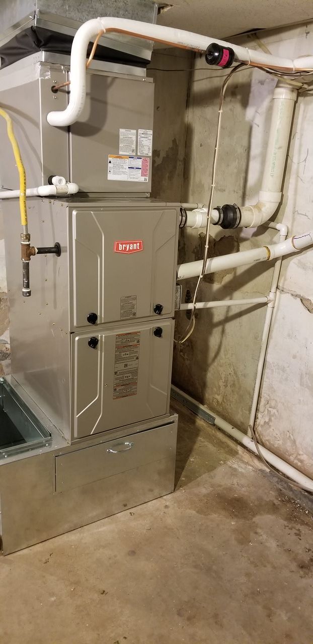 A furnace is sitting in a basement next to a wall.