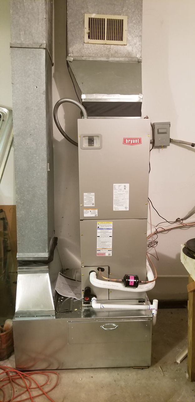 A stainless steel air conditioner is sitting in a basement.