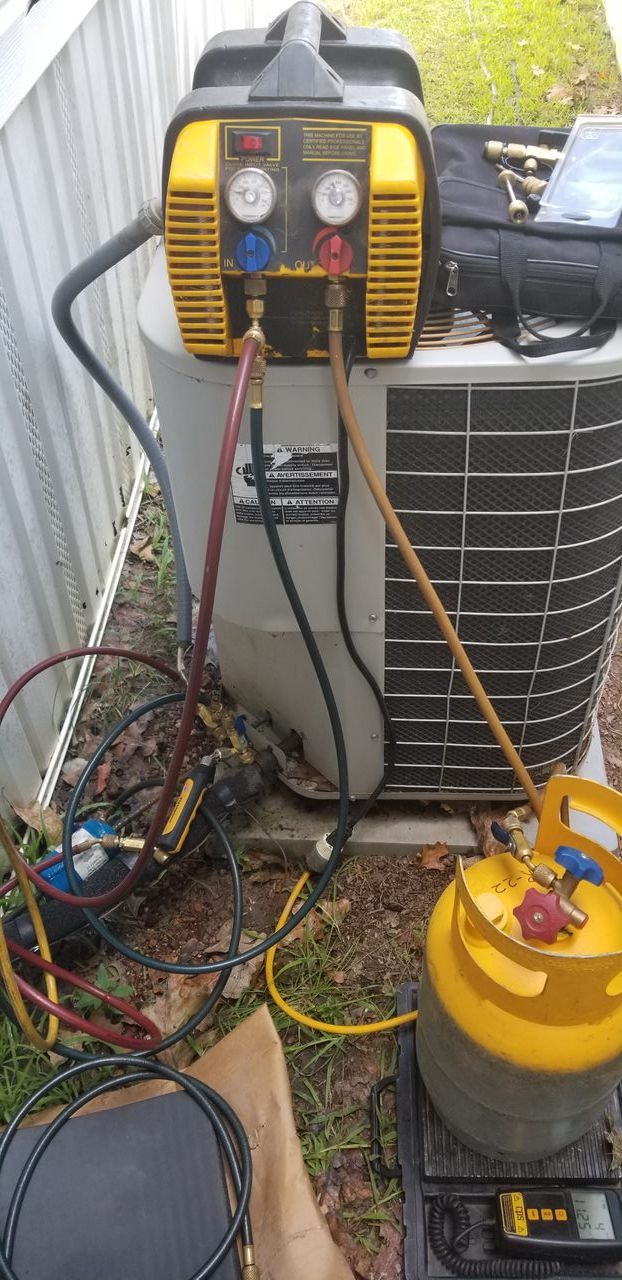 A yellow and black machine is being used to refill an air conditioner.