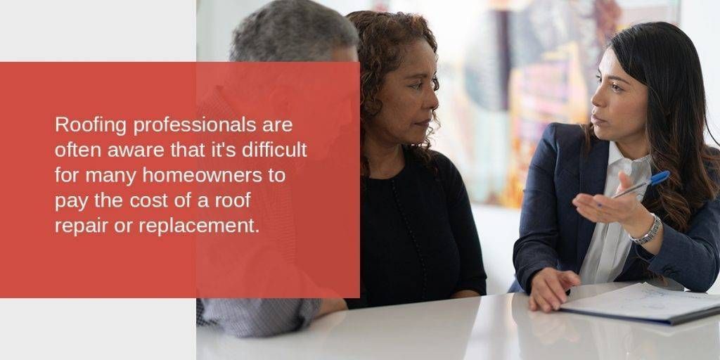 A roofer consulting with two homeowners about roof repair costs.