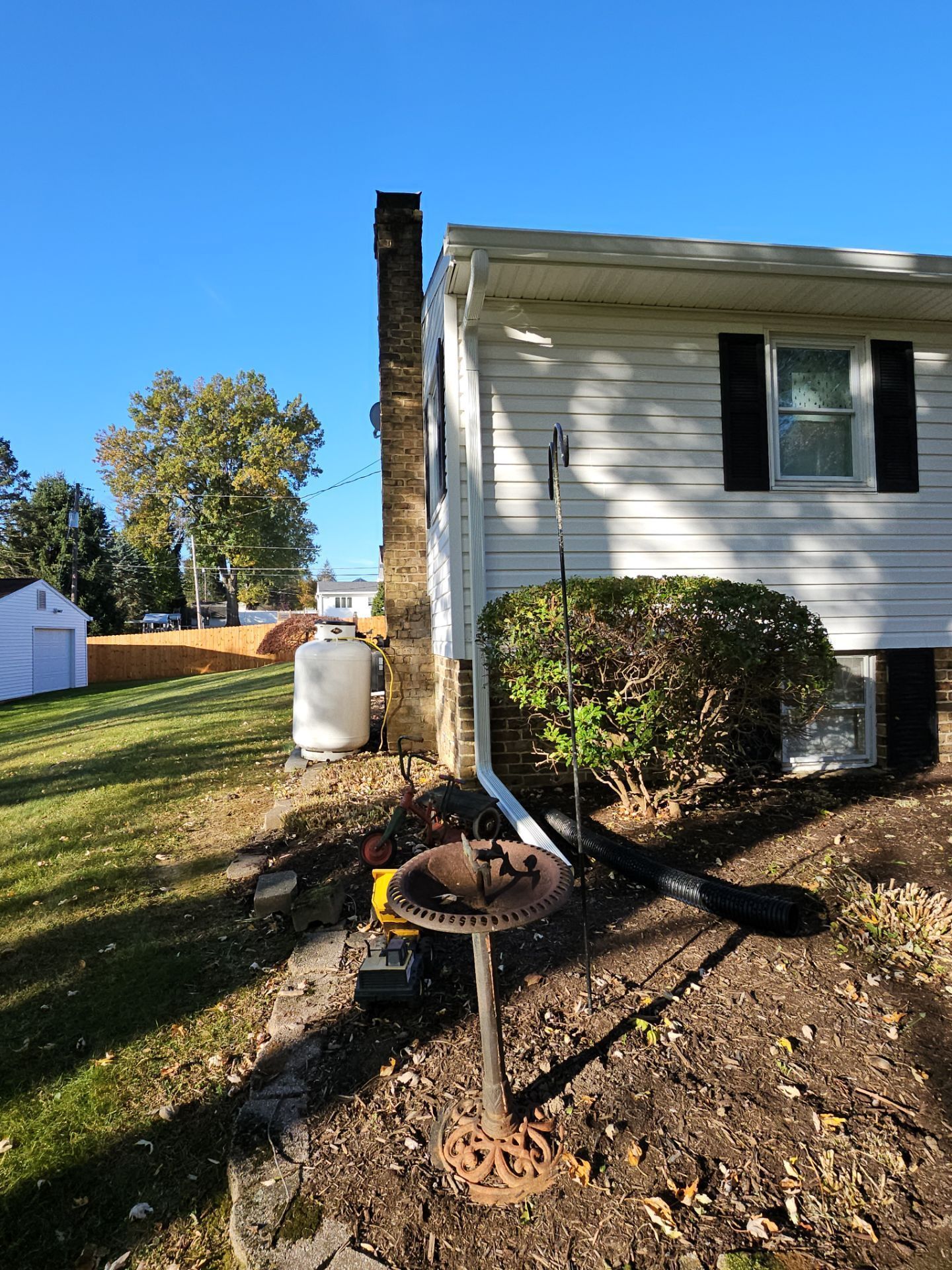 House exterior with brick chimney, propane tank, and decorative yard pieces.
