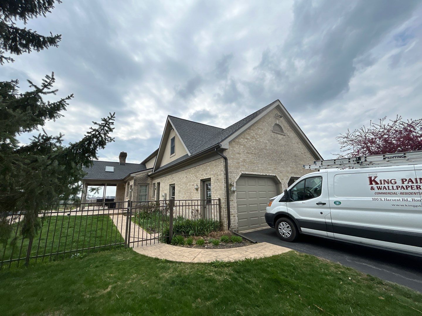 White van parked near a brick house under a cloudy sky.