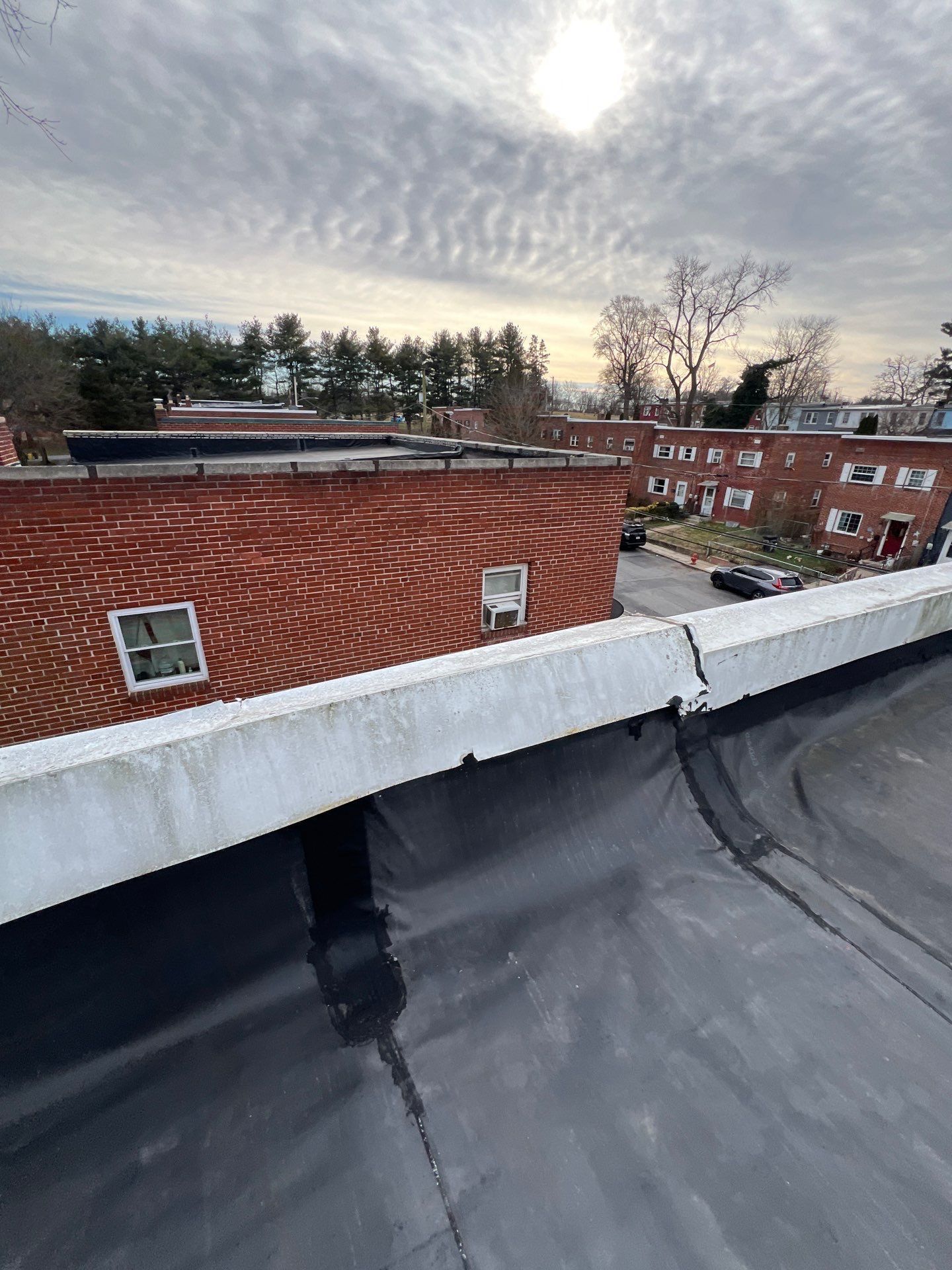 View from a flat roof, showing brick buildings and a cloudy sky.