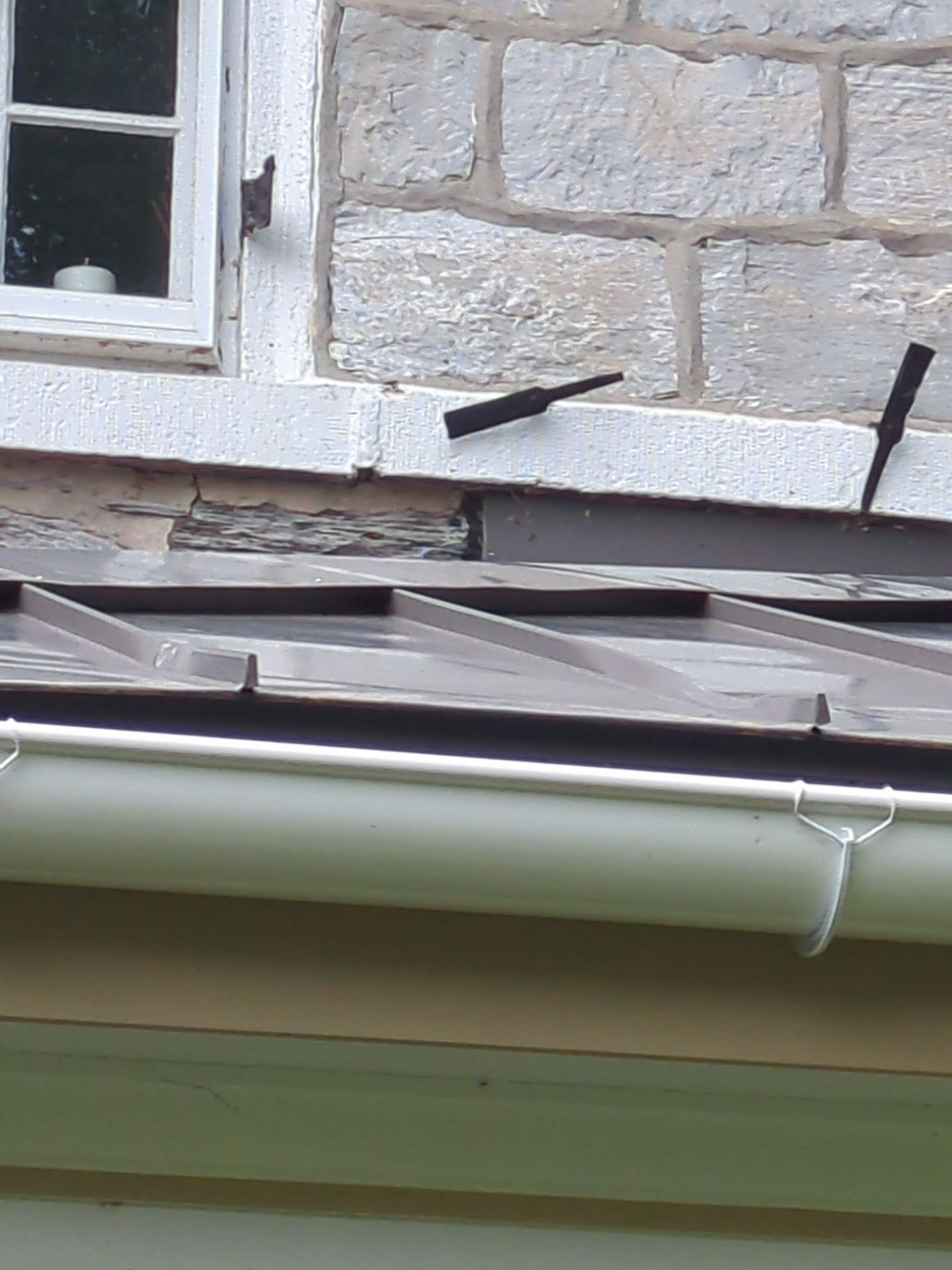 Stone building exterior with dark metal roof and white gutters.