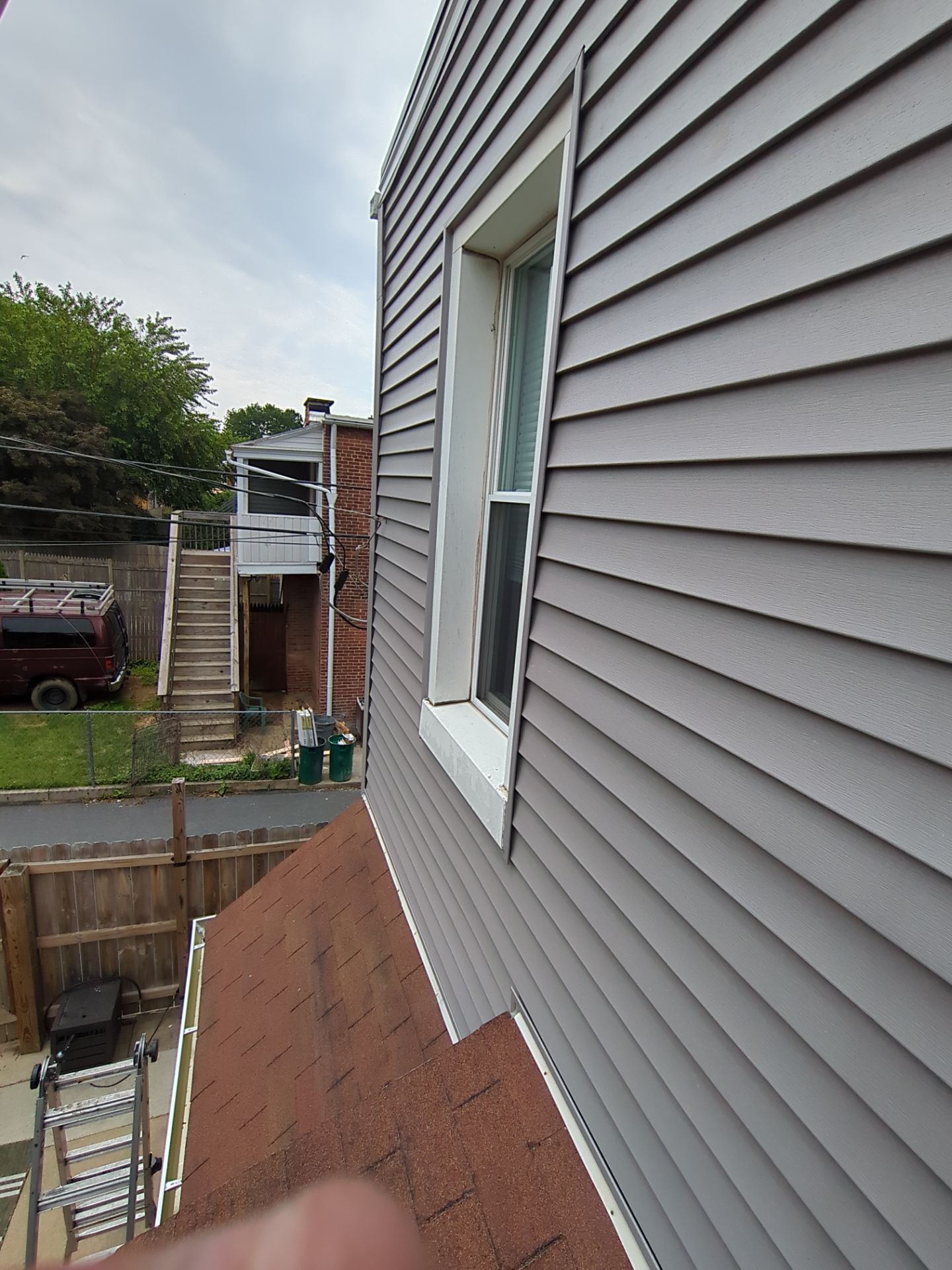 Gray siding on a building with a white-framed window. A red roof is in the foreground.