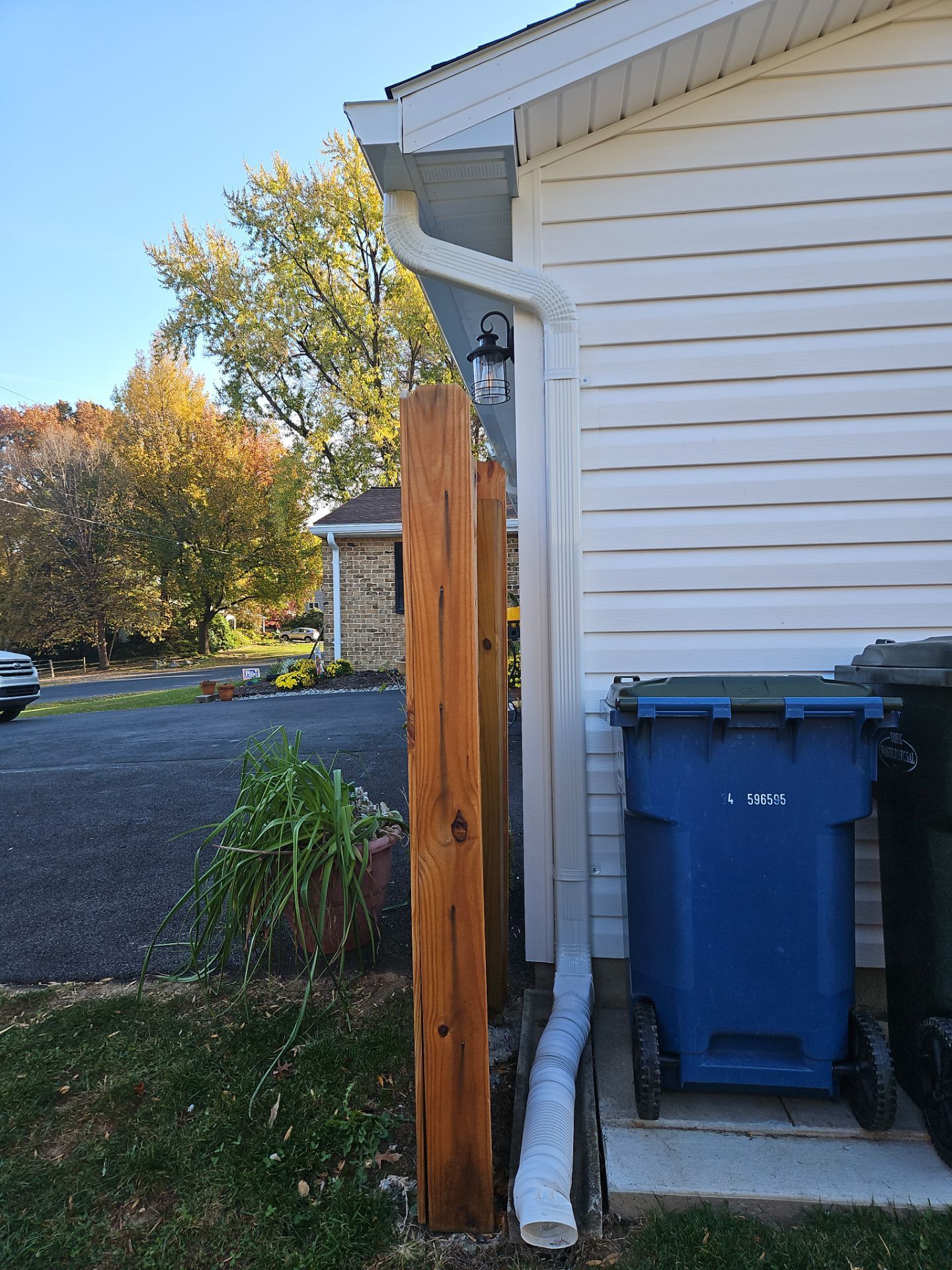 Two brown wooden posts next to a white house with a blue trash bin.