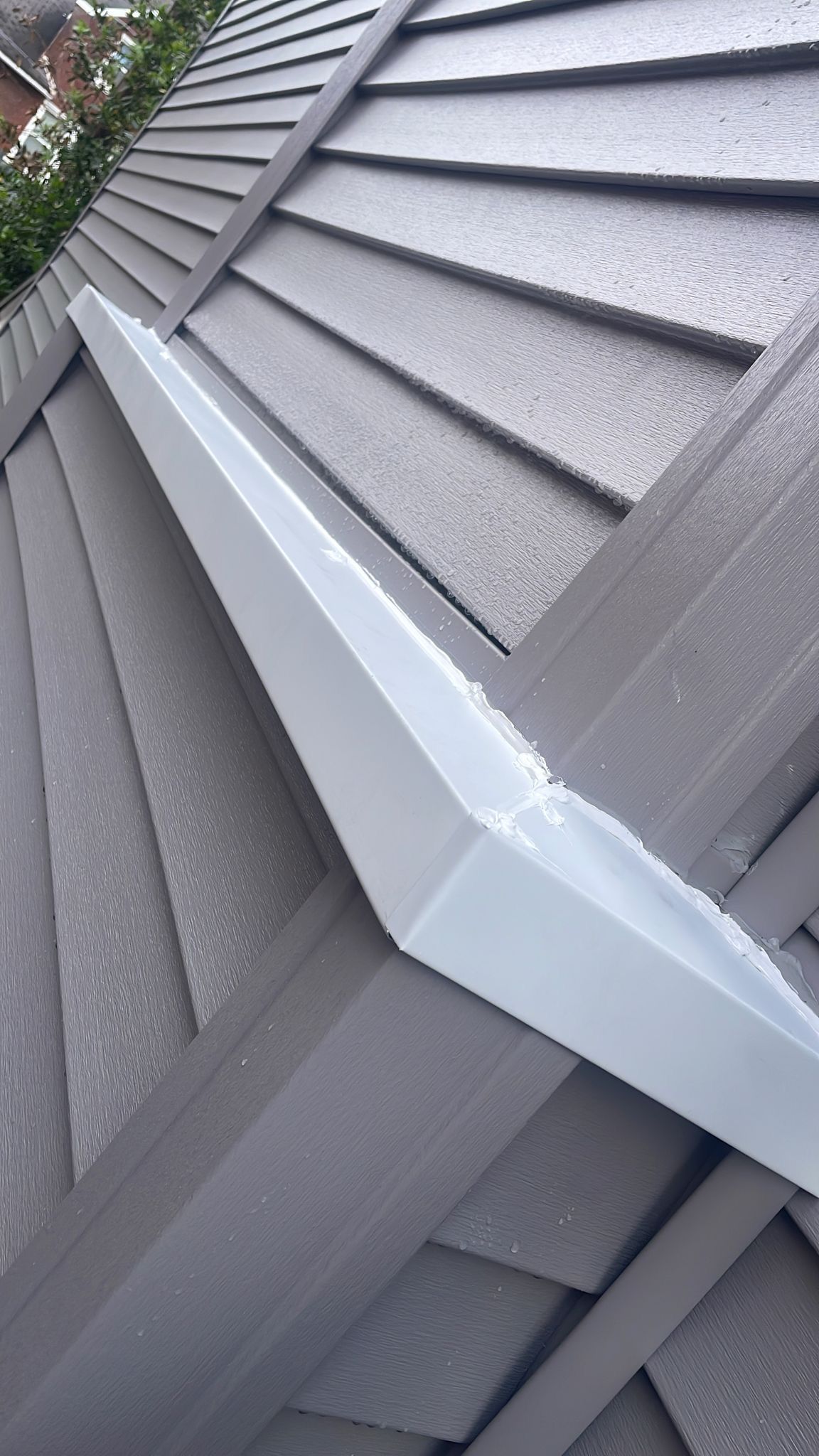 Close-up of a gray roof with a metallic-looking, angular gutter.
