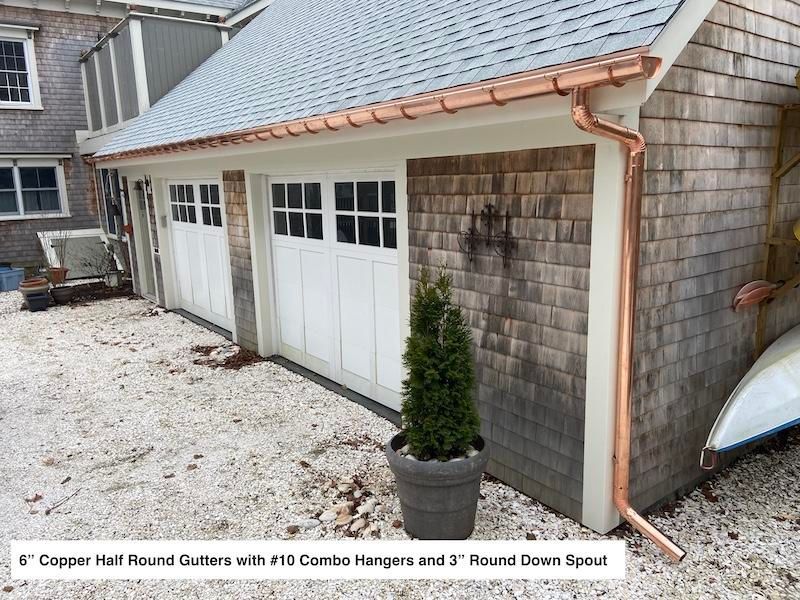 Black metal roof on a white house, aerial view. Exterior features a chimney, green lawn, and trees.