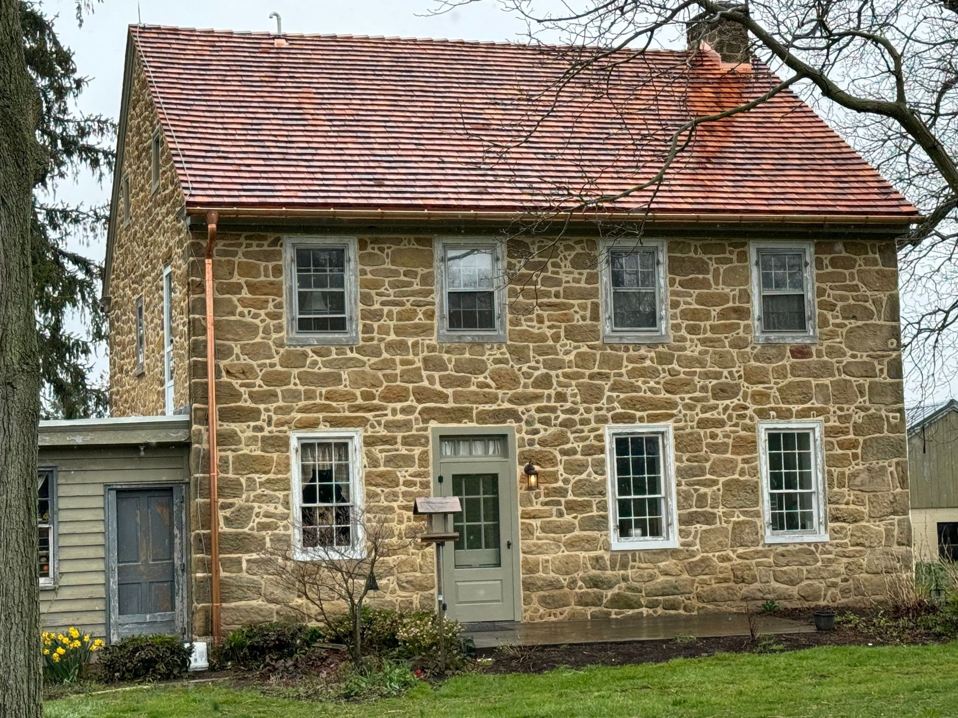 Stone house with red tile roof and multiple windows.