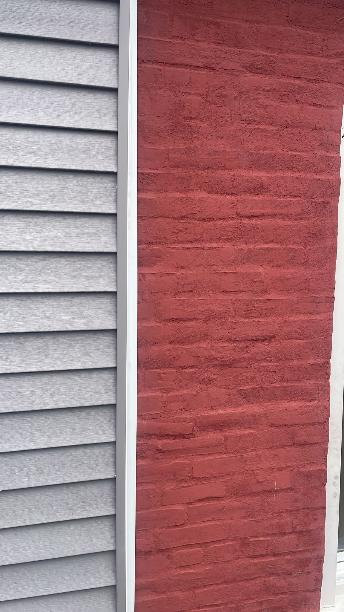 Gray siding and red brick exterior walls separated by a white vertical border.