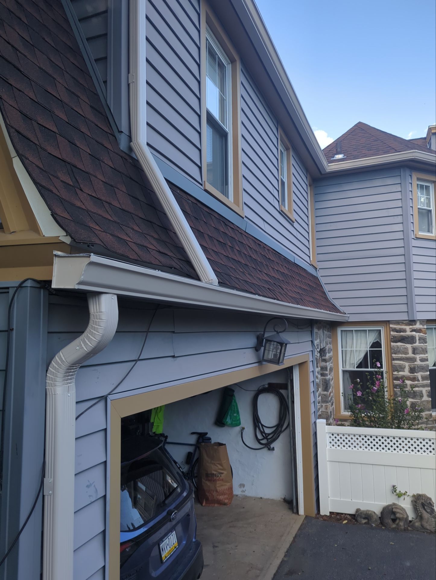 Exterior of a house with a garage, blue siding, brown roof, and white gutters.