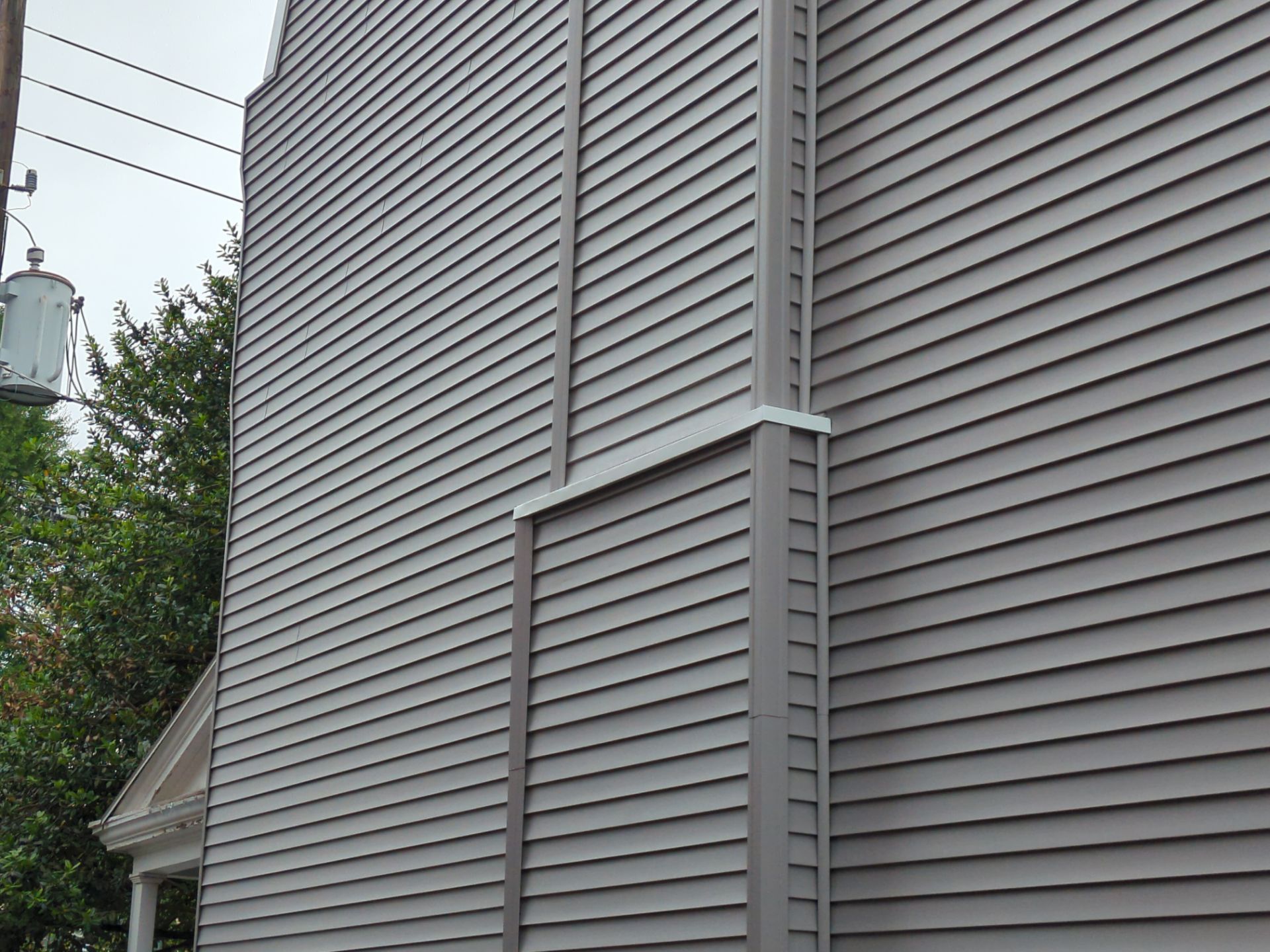 Gray siding on the side of a building with vertical trim.
