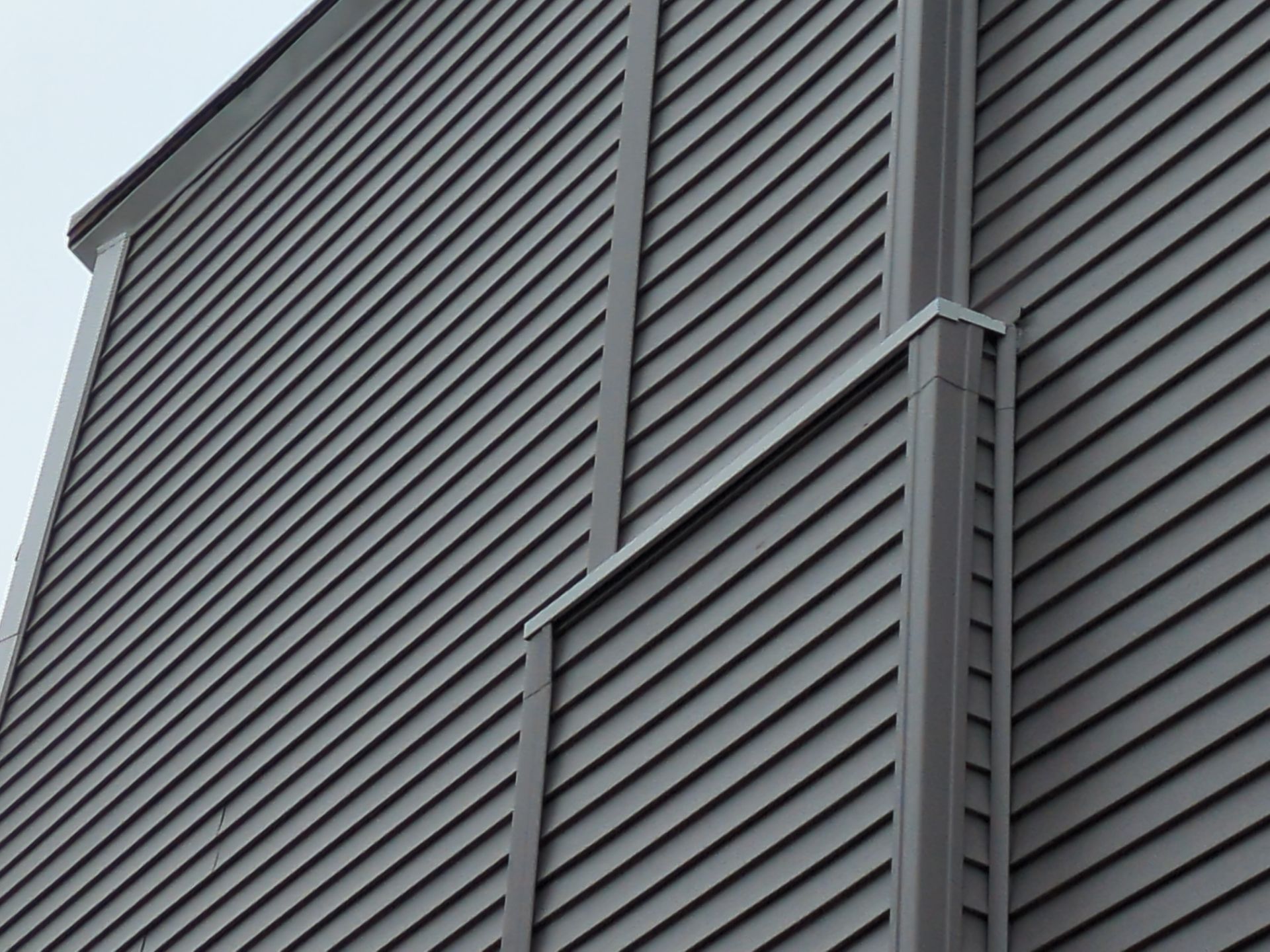 Gray building exterior with angled siding and vertical trim.