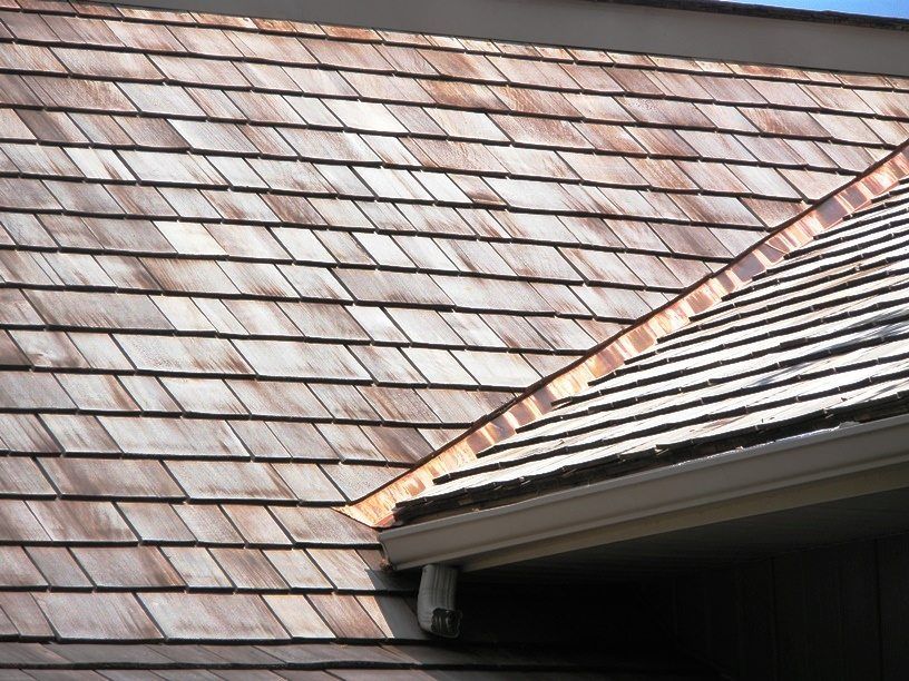 Wooden shake roof with copper flashing, close-up view.