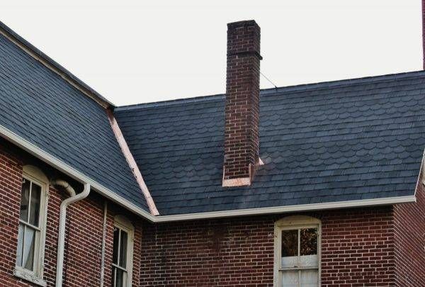 Red brick building with a dark shingle roof and a tall brick chimney.
