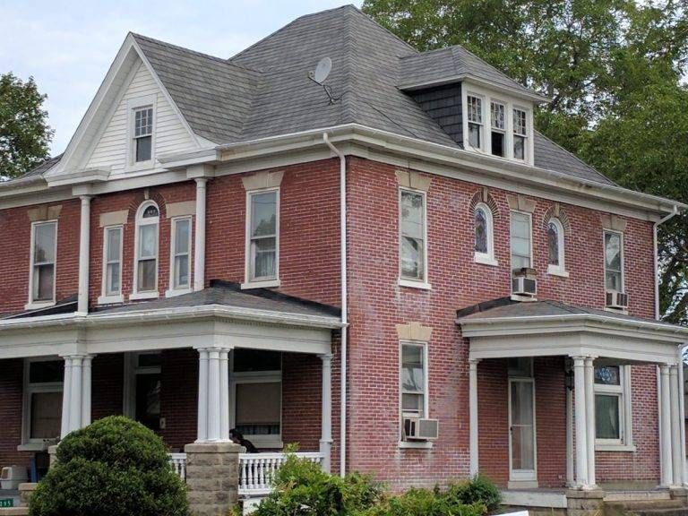 Two-story brick house with white trim, porch, and a gray roof.