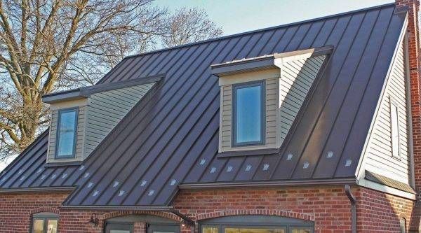 Brown metal roof with two dormers, on a brick house. Dormers have windows with blue trim.