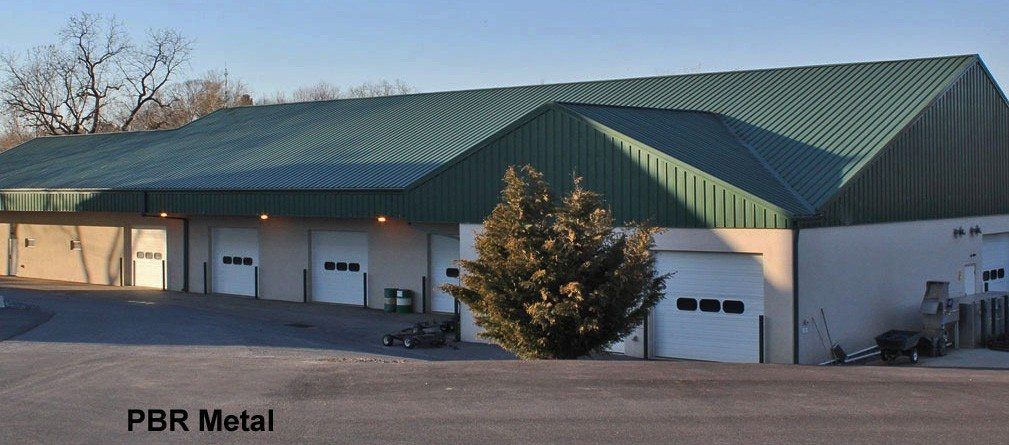House with stone facade, partial wood shingle roof, green lawn, blue sky, trees.
