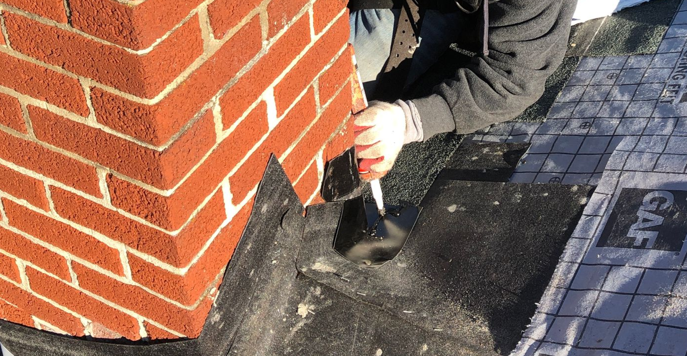 Overhead view of a house roof with sections of gray and blue metal roofing.